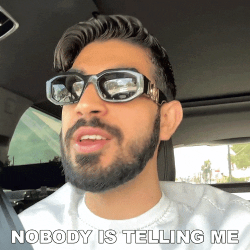 a man with a beard wearing sunglasses and a white shirt says nobody is telling me