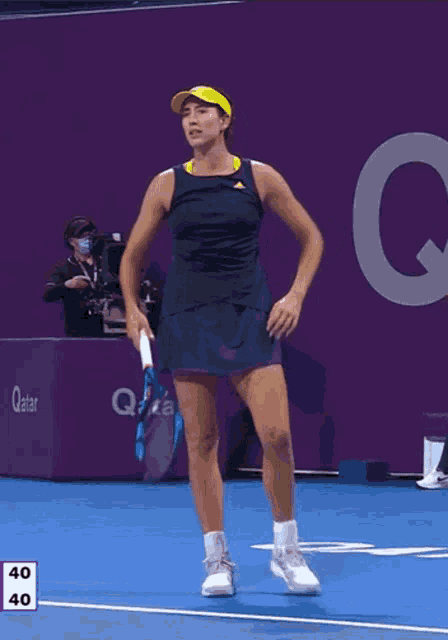 a woman is holding a tennis racquet on a court with a qatar sign in the background