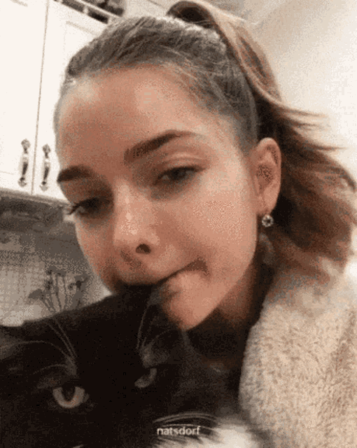 a girl with a black cat on her face and the word natsdorf on the bottom right
