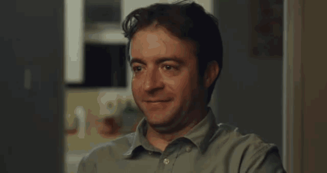 a man in a blue shirt is smiling while looking at a computer screen .