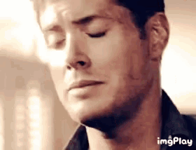 a close up of a man 's face with his eyes closed and a sad look on his face .
