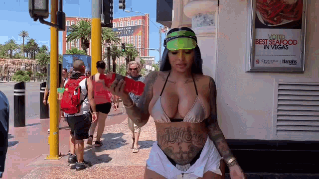 a woman in a bikini is walking down a street in front of a sign that says voted best seafood in vegas