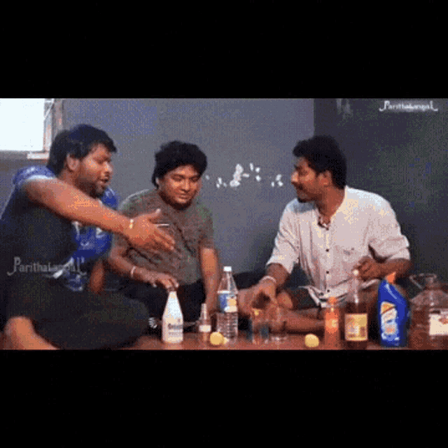 a group of men are sitting around a table with bottles of cleaning products .