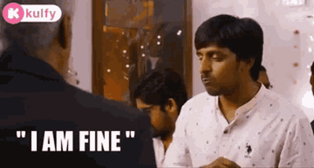 a man in a white shirt is talking to another man in a room while another man says `` i am fine '' .