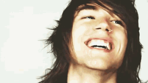 a young man with long hair is smiling and looking up at the camera .