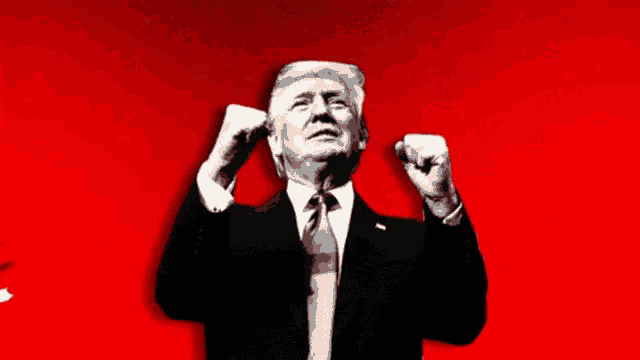 a man in a suit and tie is raising his fist up in the air