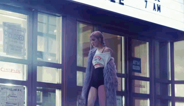 a woman in a fur coat is standing in front of a building that has a sign that says closed