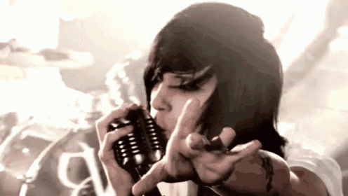 a woman is singing into a microphone while making a peace sign with her hands