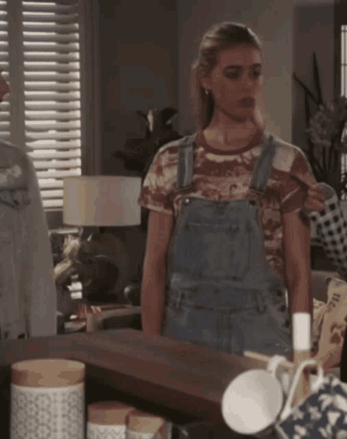 a woman wearing overalls and a t-shirt that says ' hawaii ' on it