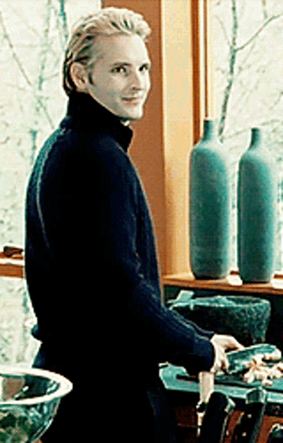 a man in a black sweater is standing in a kitchen