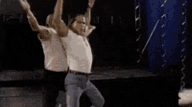two men are dancing on a stage and one is sitting on the other 's lap .