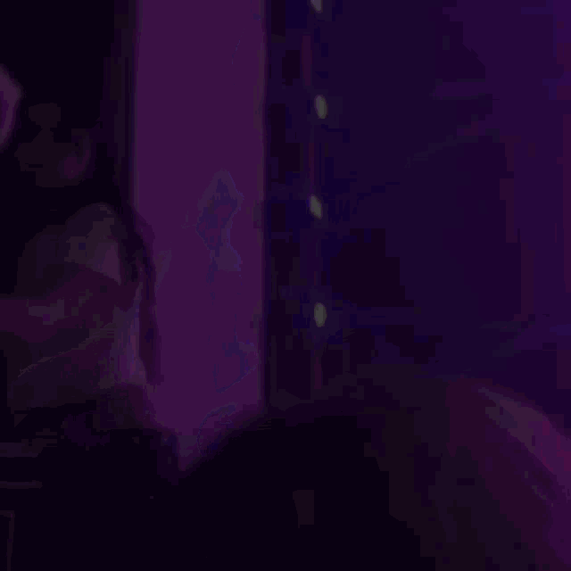 a woman is dancing on a stage in front of purple lights