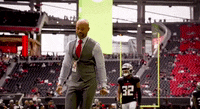 a man in a suit and tie is standing in front of a football player wearing a jersey with the number 32 on it .