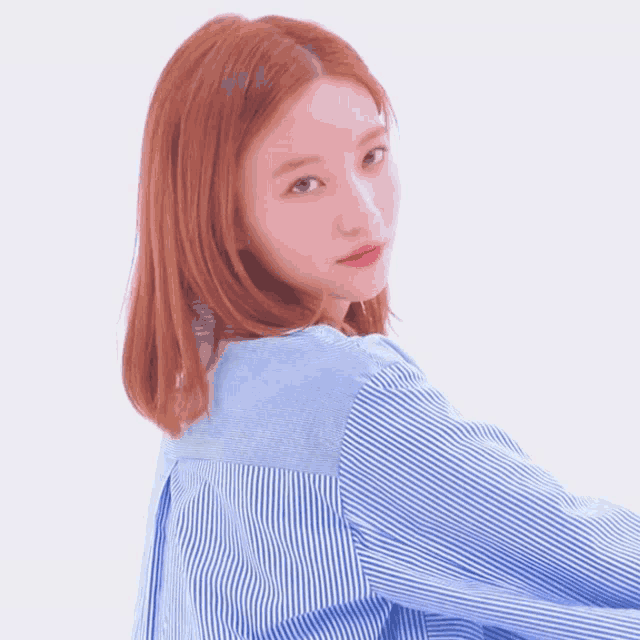 a woman in a blue and white striped shirt looks over her shoulder