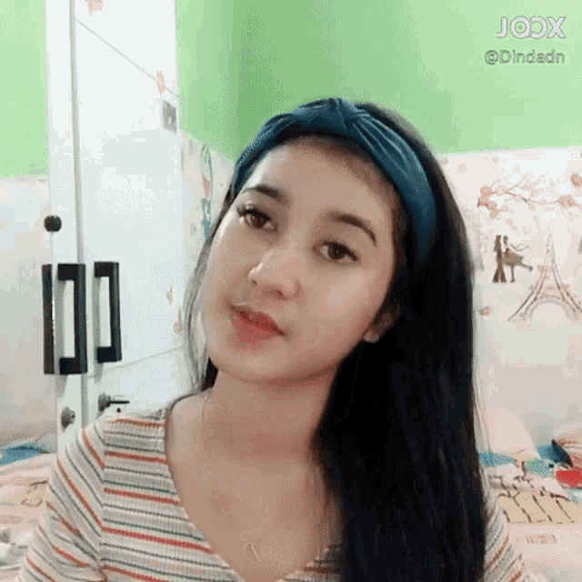 a woman wearing a headband and a striped shirt looks at the camera