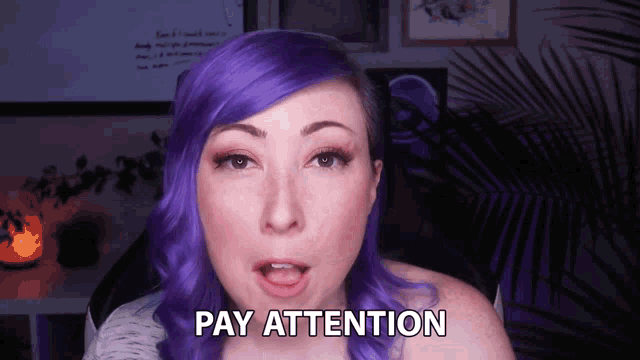 a woman with purple hair says pay attention in front of a palm tree