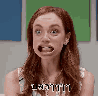 a woman with red hair is making a funny face with her mouth open in front of a green and blue background .
