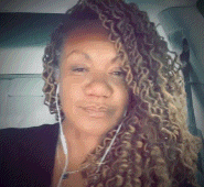 a woman with curly hair and headphones is taking a selfie in a car .