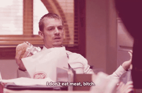 a man sitting at a table holding a bag that says i don t eat meat bitch