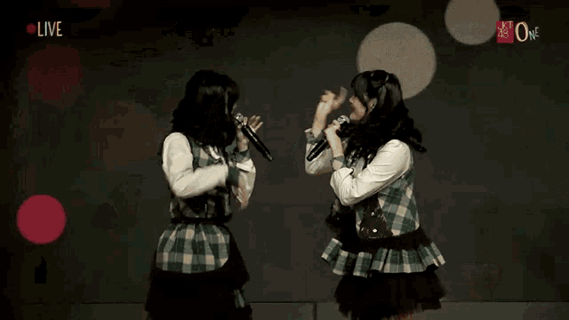 two girls singing in front of a screen that says live on it