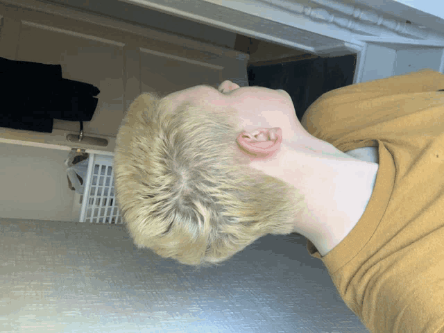 a young man with blonde hair is laying down with his head down