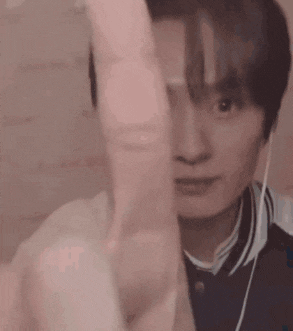 a young man wearing headphones is pointing at the camera .