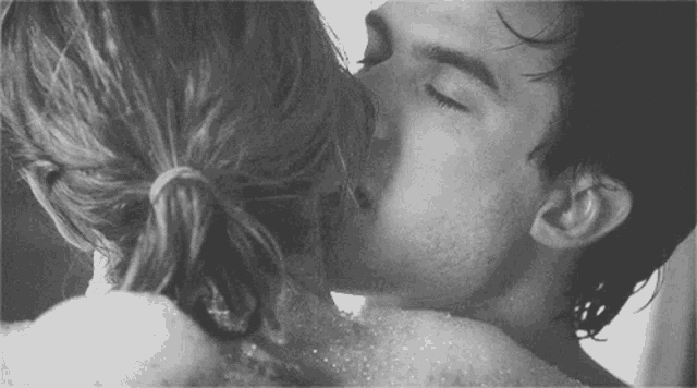 a man and woman are kissing in a bathtub filled with bubbles .