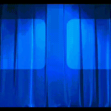 a blue curtain is being lit up by a spotlight .