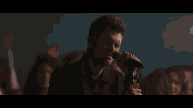 a woman singing into a microphone with a crowd in the background