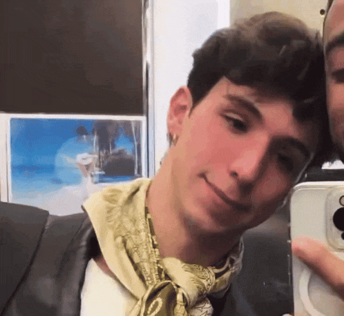 a man with a scarf around his neck takes a selfie