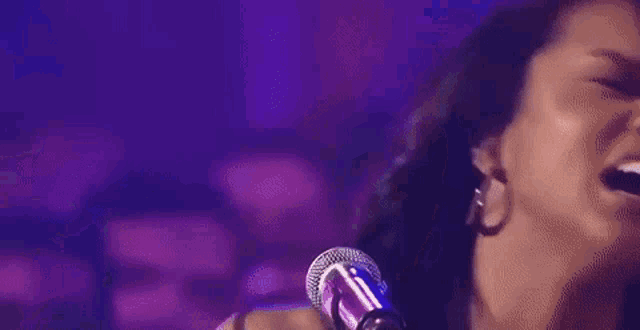 a close up of a woman singing into a microphone on a stage .