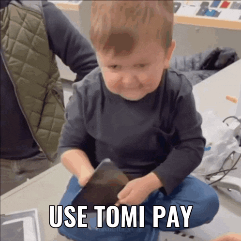 a little boy sitting on the floor with the words use tomi pay