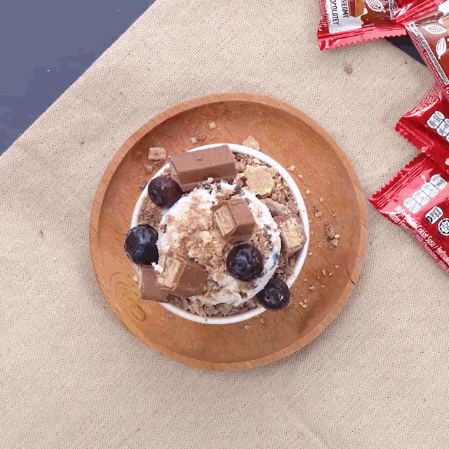 a wooden plate topped with ice cream and blueberries