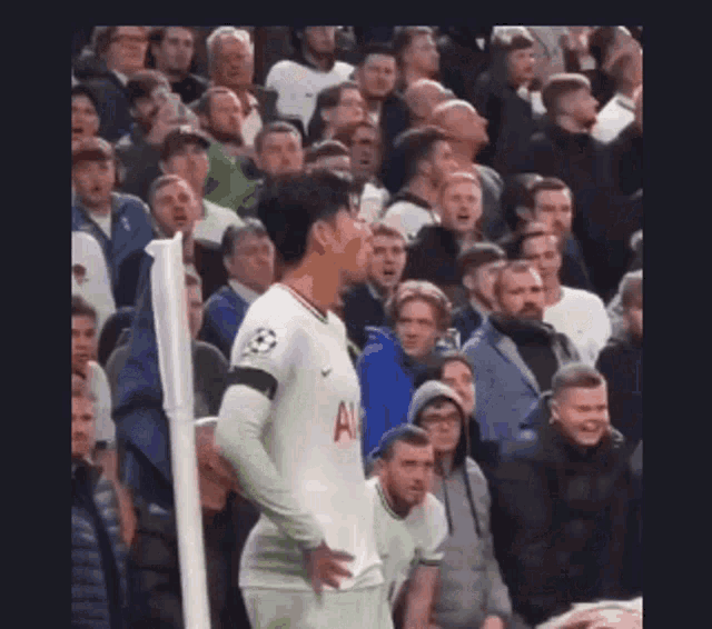 a soccer player is standing in the middle of a crowd of people .