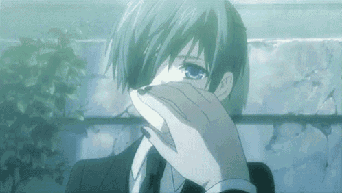 a man with blue hair is covering his face with his hand .