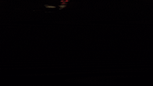 a man with a beard is sitting in a dark room and smiling .