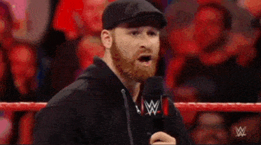 a man with a beard is standing in a wrestling ring and clapping his hands .