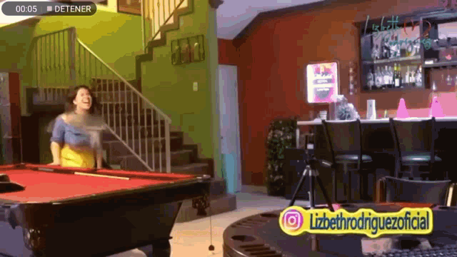 a woman is standing next to a pool table in a room with a sign that says detener
