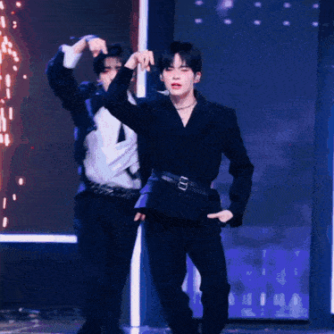 a man in a black suit is dancing with another man in a white shirt