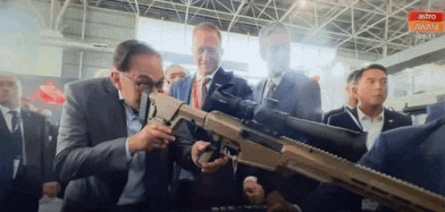 a man in a suit is looking through a scope on a gun .