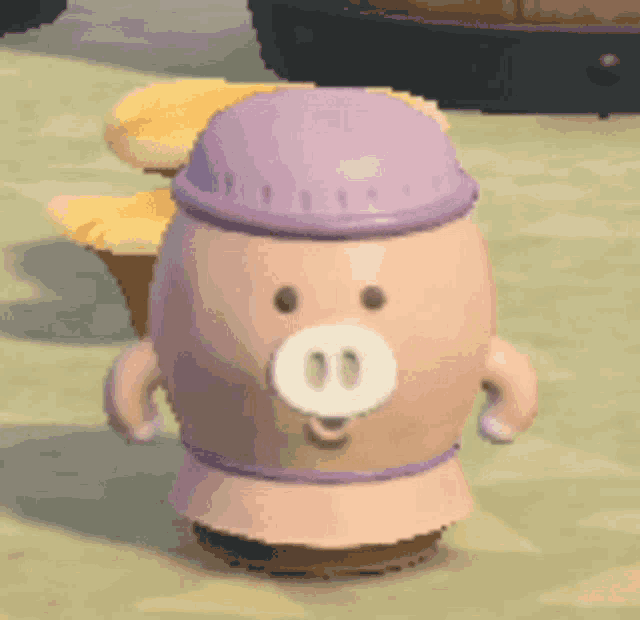 a pink pig with a purple hat and a pig nose is standing on a sandy beach .
