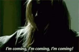 a woman in a dark room is saying i 'm coming i 'm coming i 'm coming !