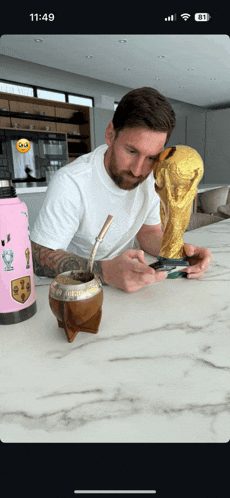 a man sits at a table with a trophy and a water bottle with a sticker on it