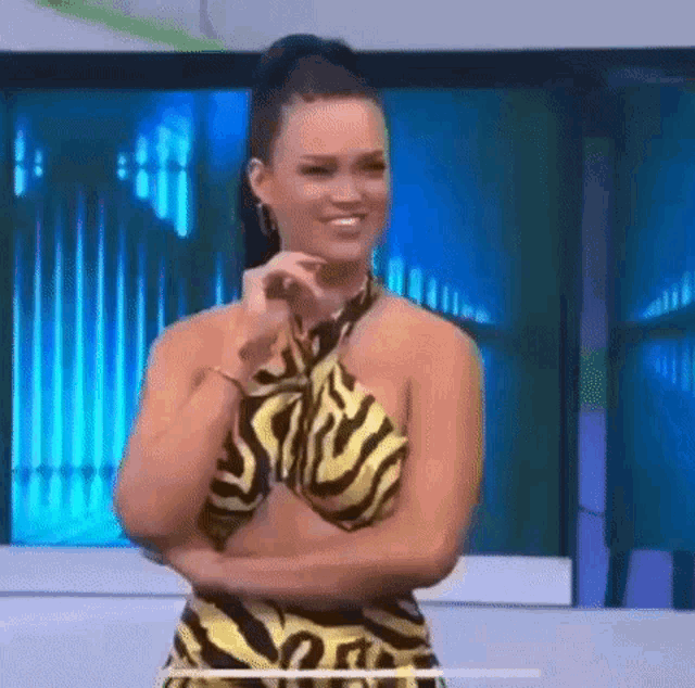 a woman in a yellow and black zebra print dress is smiling .