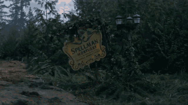 a sign for the spellman mortuary is surrounded by trees and fire