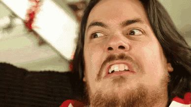 a man with long hair and a beard is making a funny face .