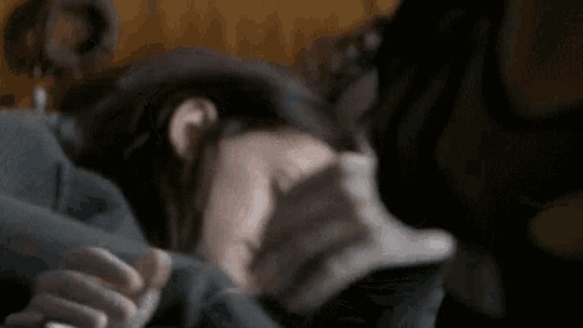 a young girl is sleeping on a bed with a person holding her hand .
