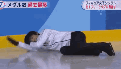 a person is laying on their stomach on a ice rink with asian writing on the bottom