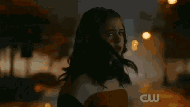a close up of a woman 's face in a dark room with a cw logo in the corner .
