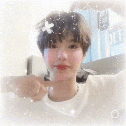 a girl with short hair is pointing at the camera with a sign in the background that says ' j.c.t. '